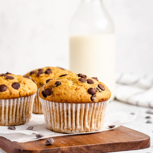 Three Bakery-Style Chocolate Chips Muffins On Wooden Board